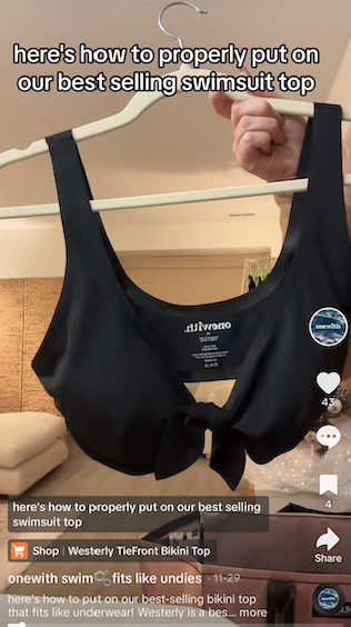 Front view of Westerly Tie-Front Bikini Top in black showcasing front tie and scoop neckline on a hanger in a living room setting