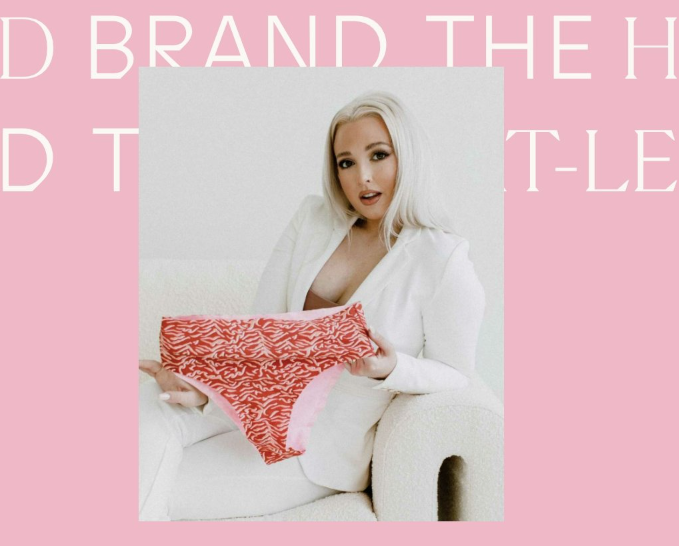 Blonde woman seated on cream sofa in white blazer holding red patterned underwear; background text 'BRAND THE'