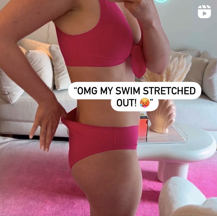 Side view of model in pink bikini showing stretched-out bottom at the hip with couch and pink rug in background