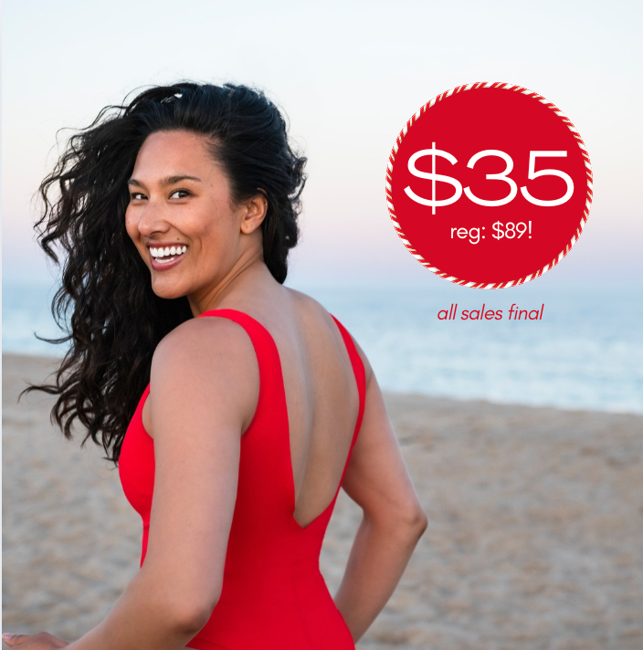 Back view of Bellows in Cherrydip red one-piece showing low scoop back on a beach with a red sale badge