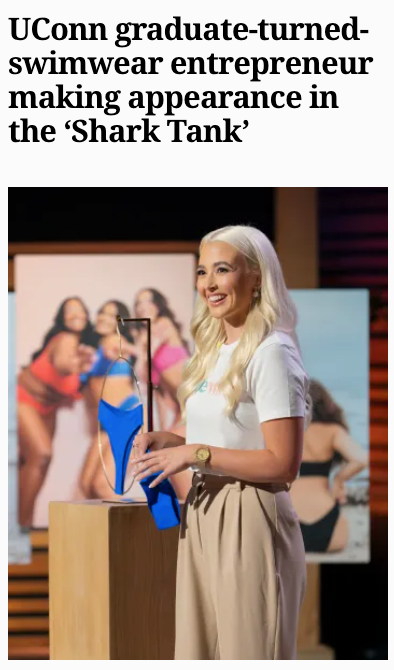 onewith founder presenting a blue one-piece swimsuit on the Shark Tank stage with a blurred swimsuit photo backdrop