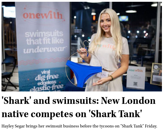 Hayley Segar wearing a OneWith t-shirt holding a blue swimsuit in front of a banner reading 'onewith. swimsuits that fit like underwear'.