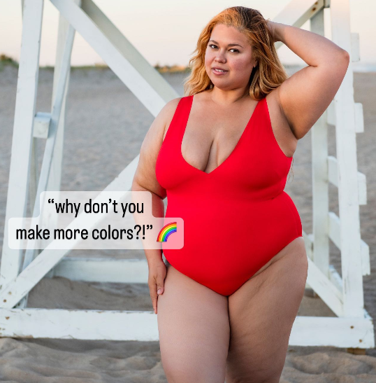 Front view of red one-piece swimsuit on plus-size model showing scoop neckline and full coverage at lifeguard stand on beach