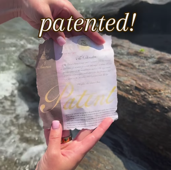 Hands holding a weathered paper on rocky shore, overlaid text 'patented!'