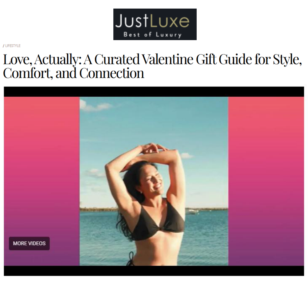 Smiling woman in a black bikini standing by the ocean with raised arms; banner reading JustLuxe. Love, Actually: A Curated Valentine Gift Guide for Style, Comfort and Connection