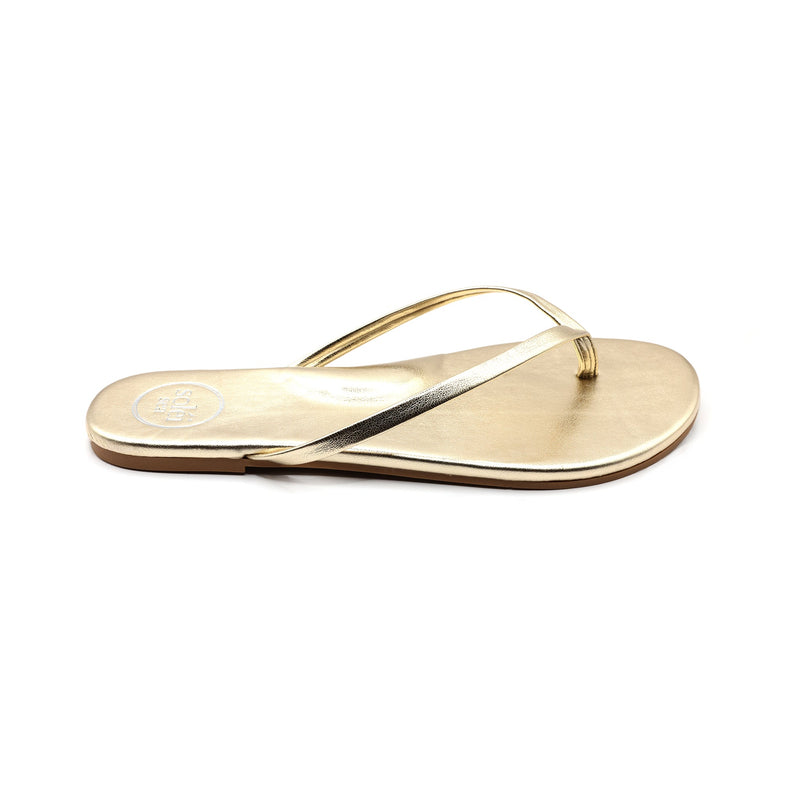Metallic gold thong sandal with thin straps and low sole on white background