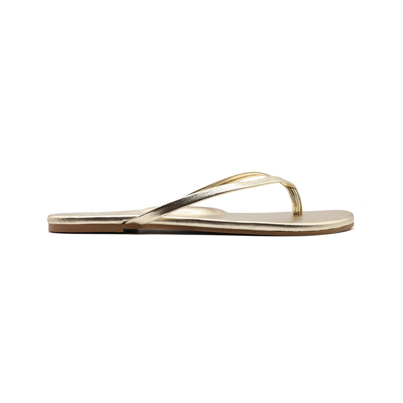 Metallic gold thong sandal on white background, side view.
