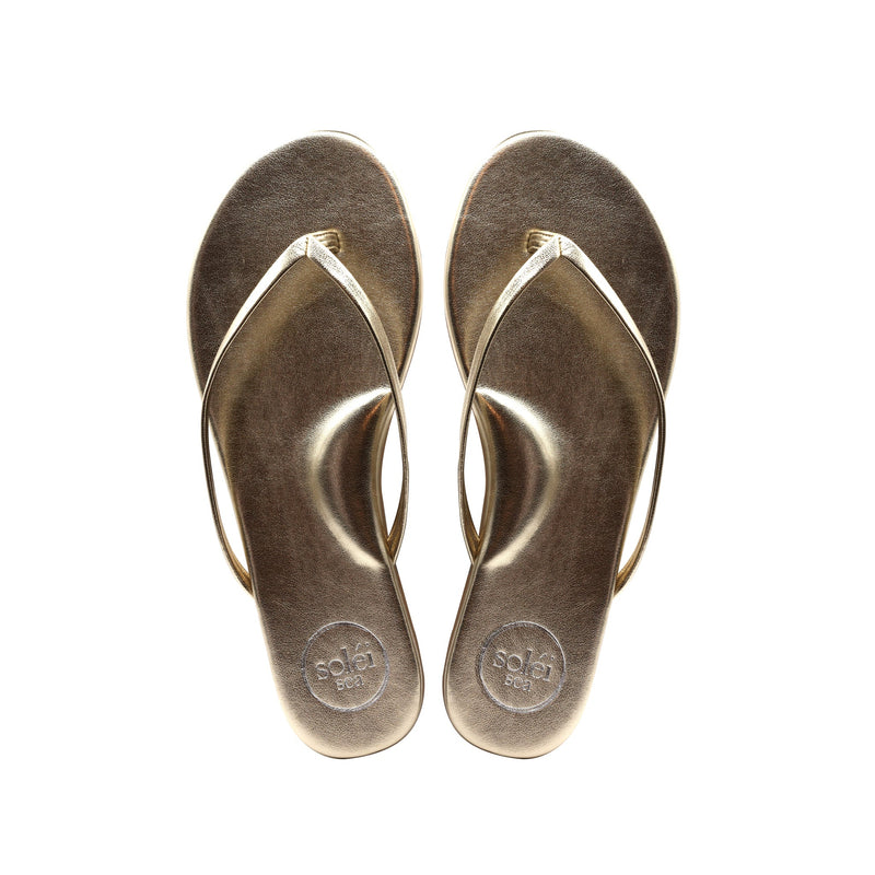 Top-view of a pair of brown flip-flops with circular logos on the heels
